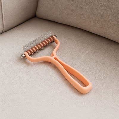 Brosse pour Chat orange posée sur le divan 