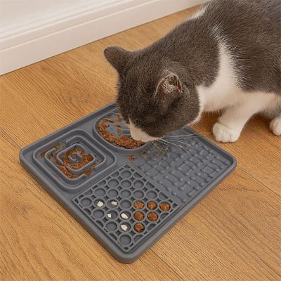 chat mangeant dans le Tapis de lechage chat gris