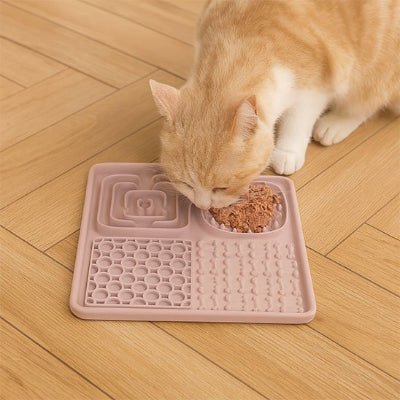chatte rousse mangeant dans le Tapis de lechage chat