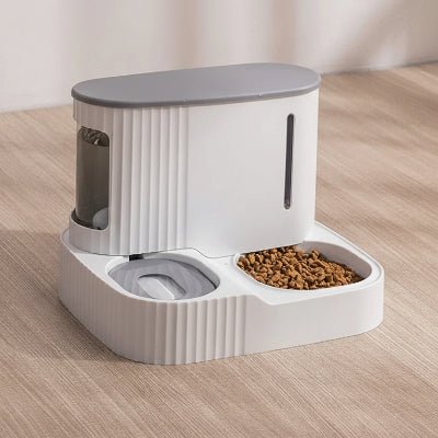 distributeur de croquettes gris posé sur un parquet 