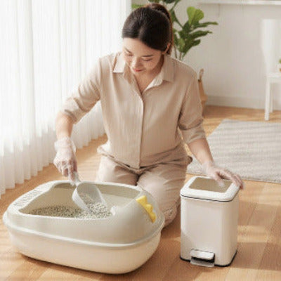 Une madame nettoie le bac a litiere pour chat.