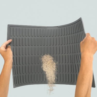 une main secoue le tapis litiere chat